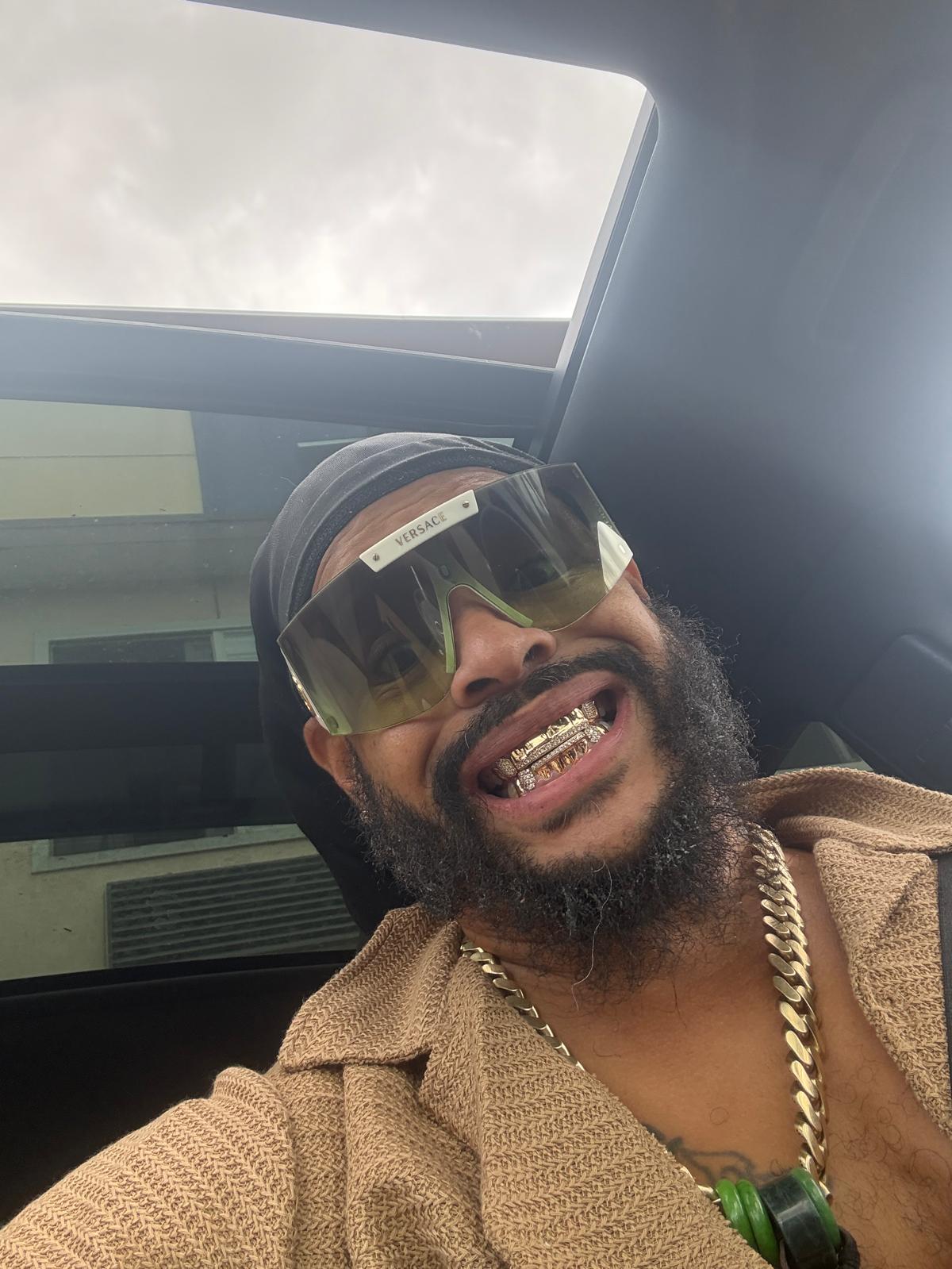 PRECYSE wearing sunglasses and a tan jacket